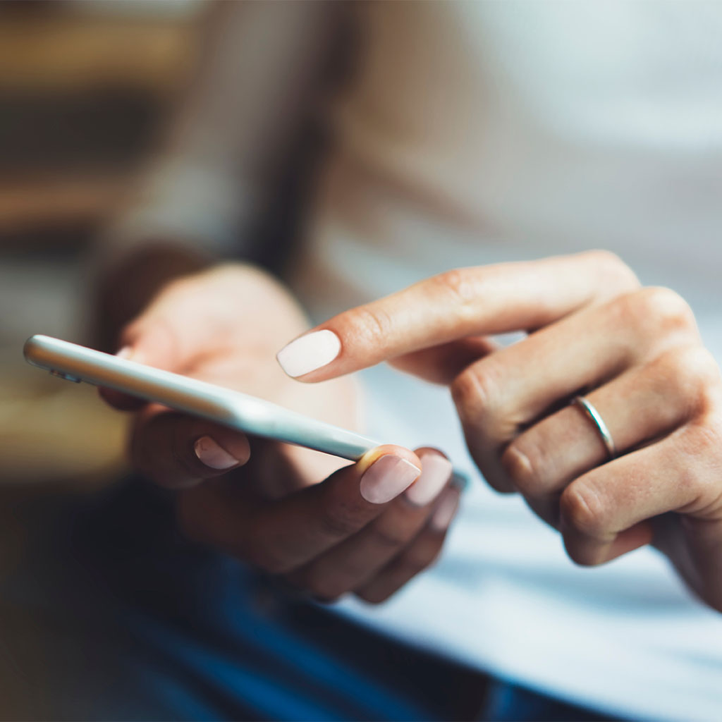 Hand holding a smartphone at an angle, representing a customer reading content online.