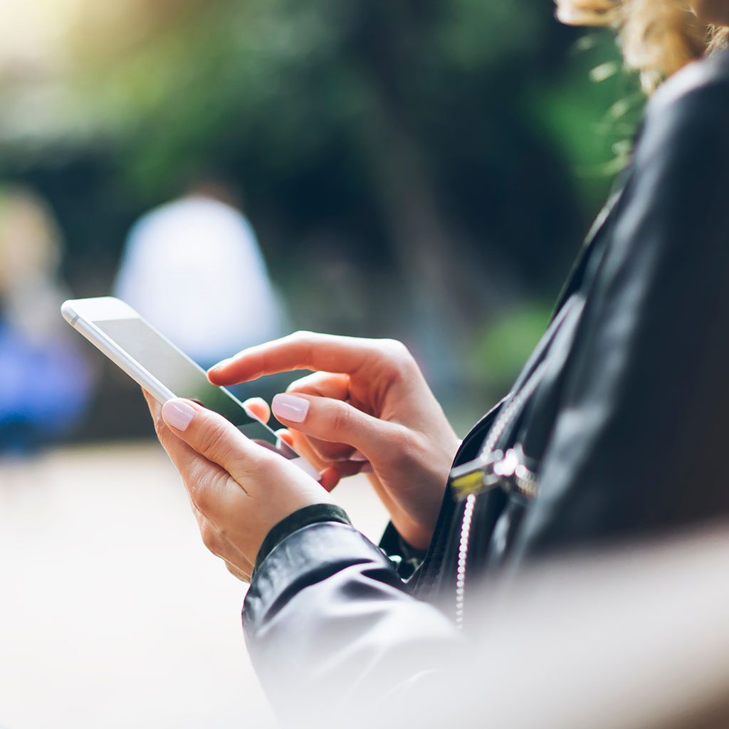 Business professional checking a phone outdoors, representing a client reviewing digital PR coverage.