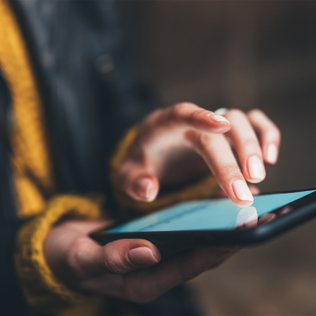 Close-up of a hand touching a smartphone with a soft glowing screen, representing a customer found through our internet marketing service.