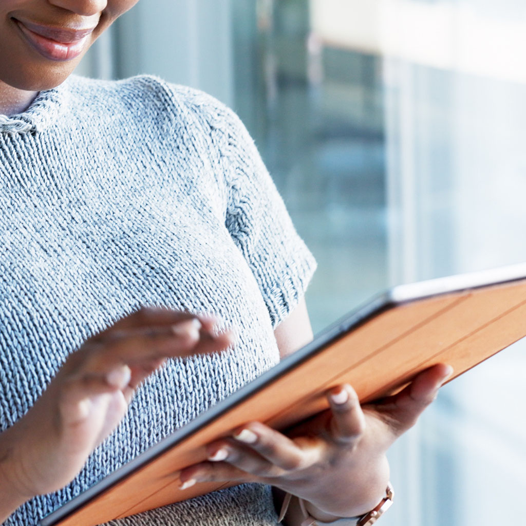 Woman smiling while holding a tablet, representing a customer reached by a PPC ad campaign.
