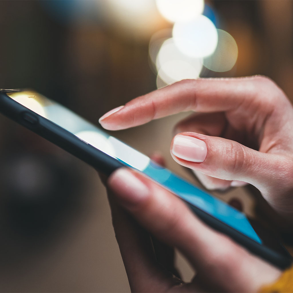 Hand tapping a smartphone screen with a soft glow, representing a customer reading content online.