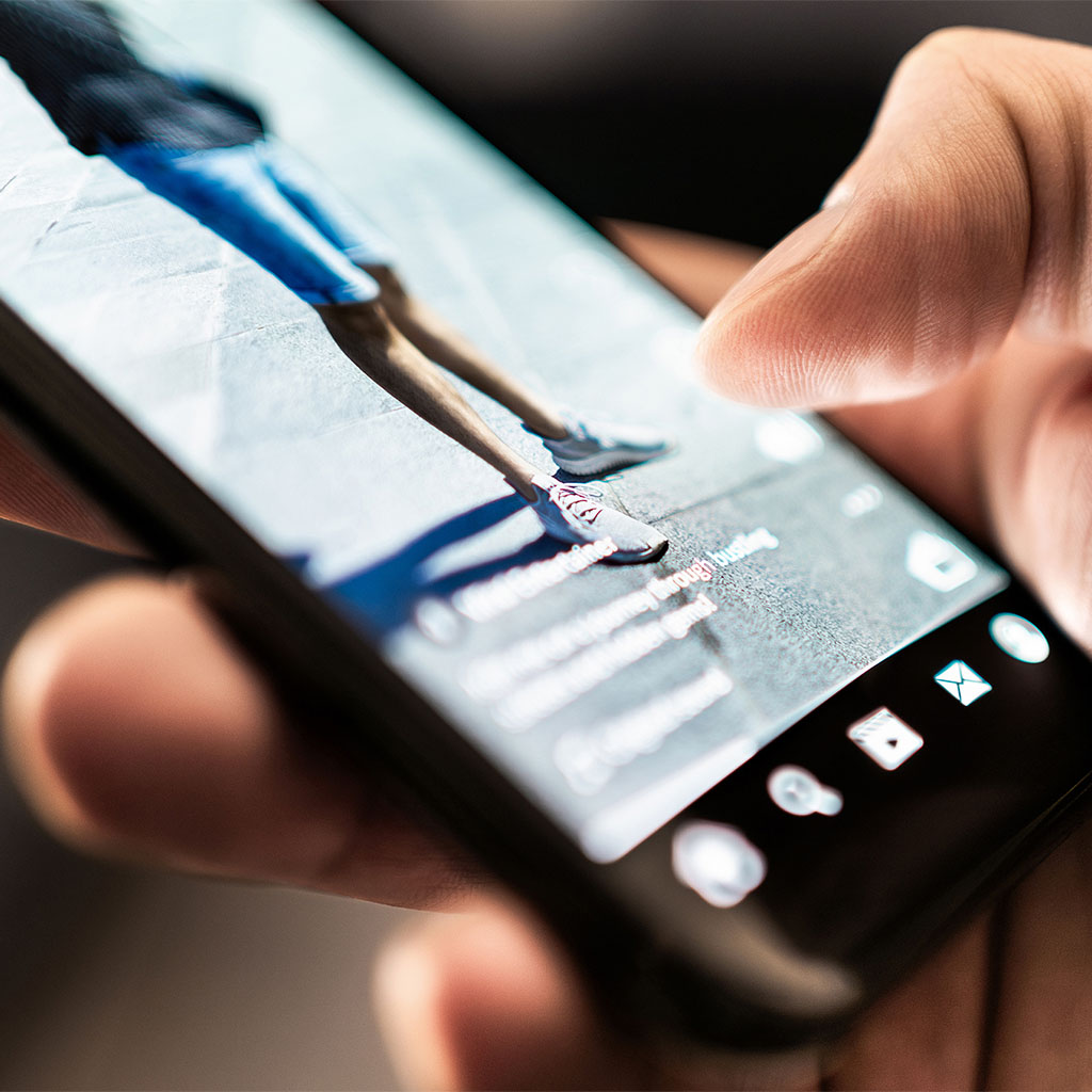 Hand scrolling a short-form video app on a smartphone, representing a customer engaging with video content.